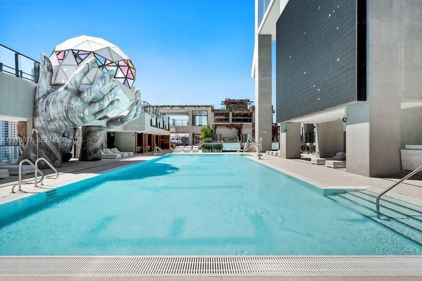 Rooftop swimming pool featuring a geometric dome sculpture, integrated stair entry, tiled surround, and structural pillars