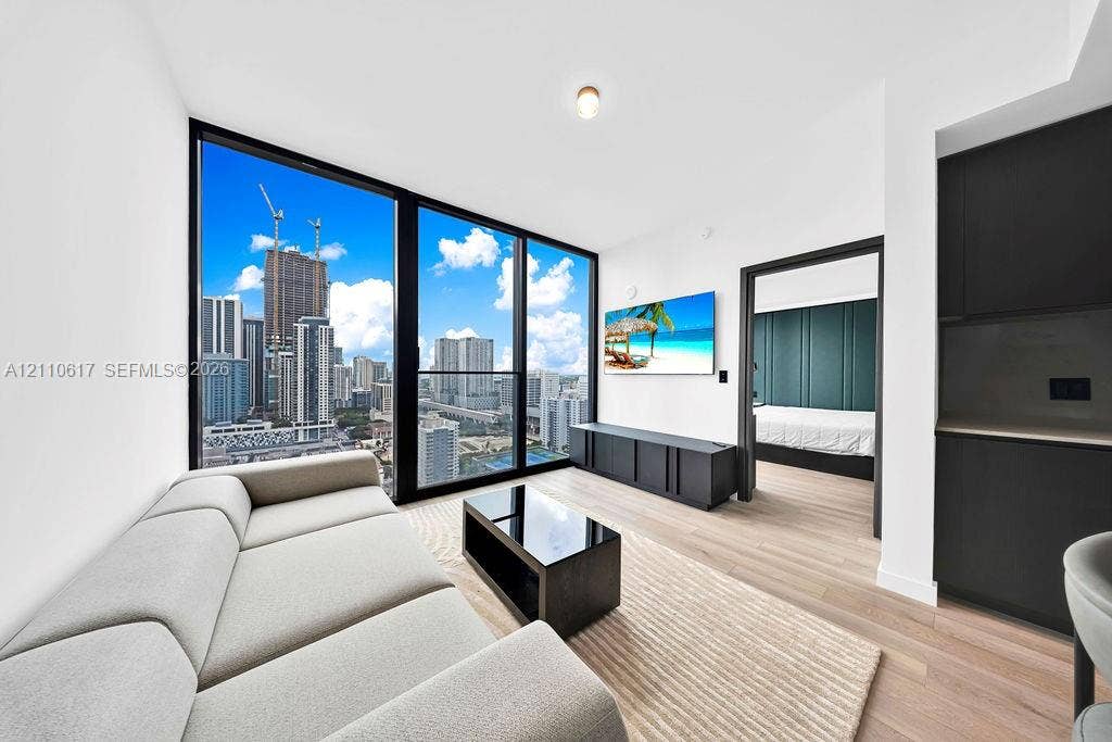 Floor-to-ceiling windows, wood-finish flooring, and black cabinetry