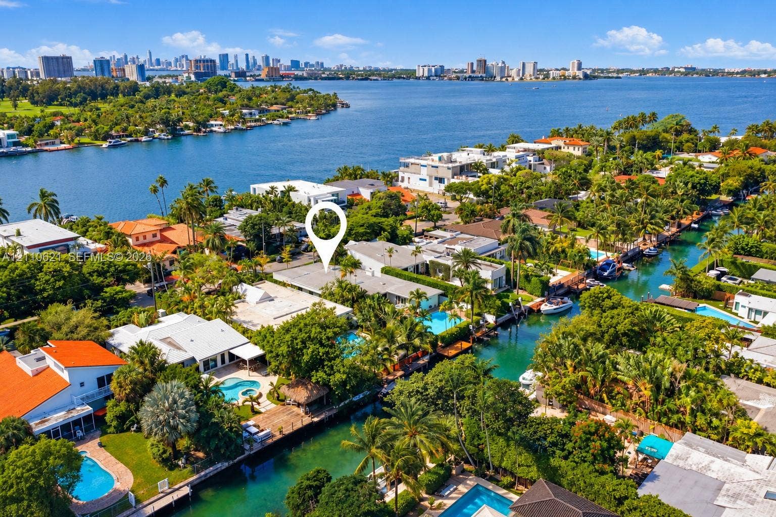 Aerial perspective of a waterfront property featuring a private swimming pool, deep-water canal access, and mature landscaping
