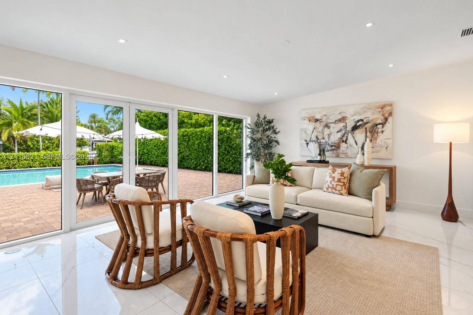 Interior space featuring white tile flooring, recessed lighting, and expansive floor-to-ceiling glass sliding doors opening to a brick-paved pool area