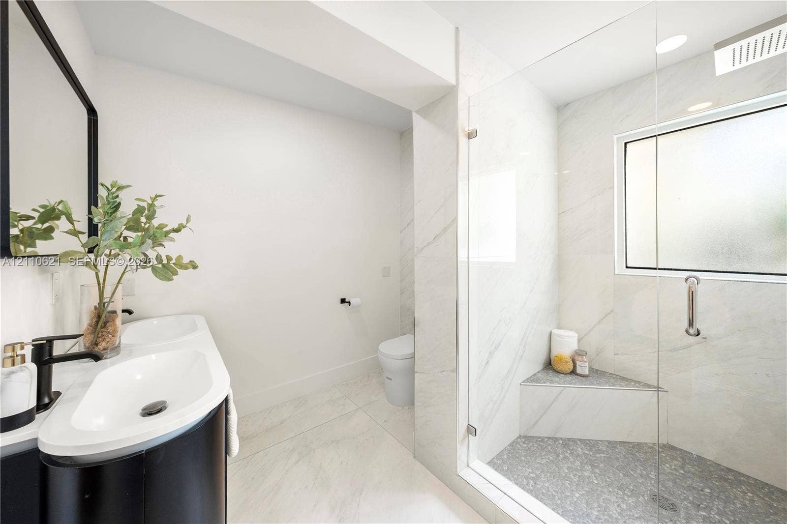 Dual-sink vanity with matte black fixtures, walk-in shower with frameless glass enclosure, built-in shower bench, and large-format tile flooring