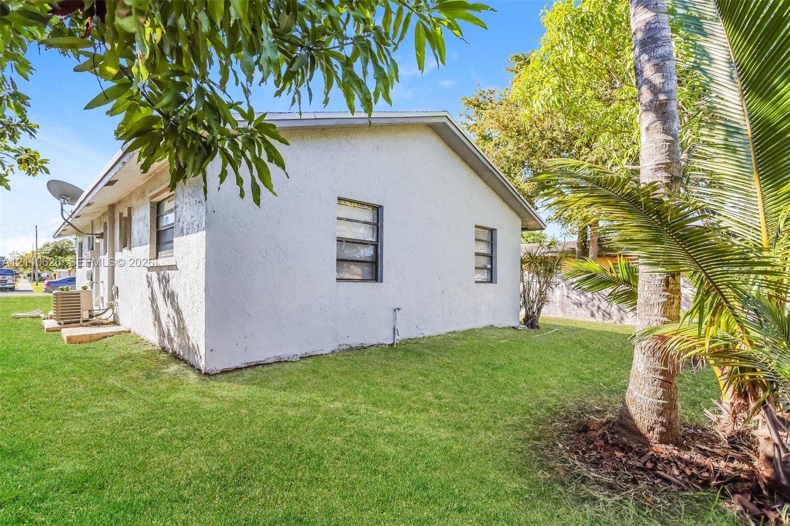 1301 NW 2nd Street, Dania, Dania Beach, FL 33004 Stucco exterior featuring dual-pane windows, a gabled roofline, and manicured turf grass