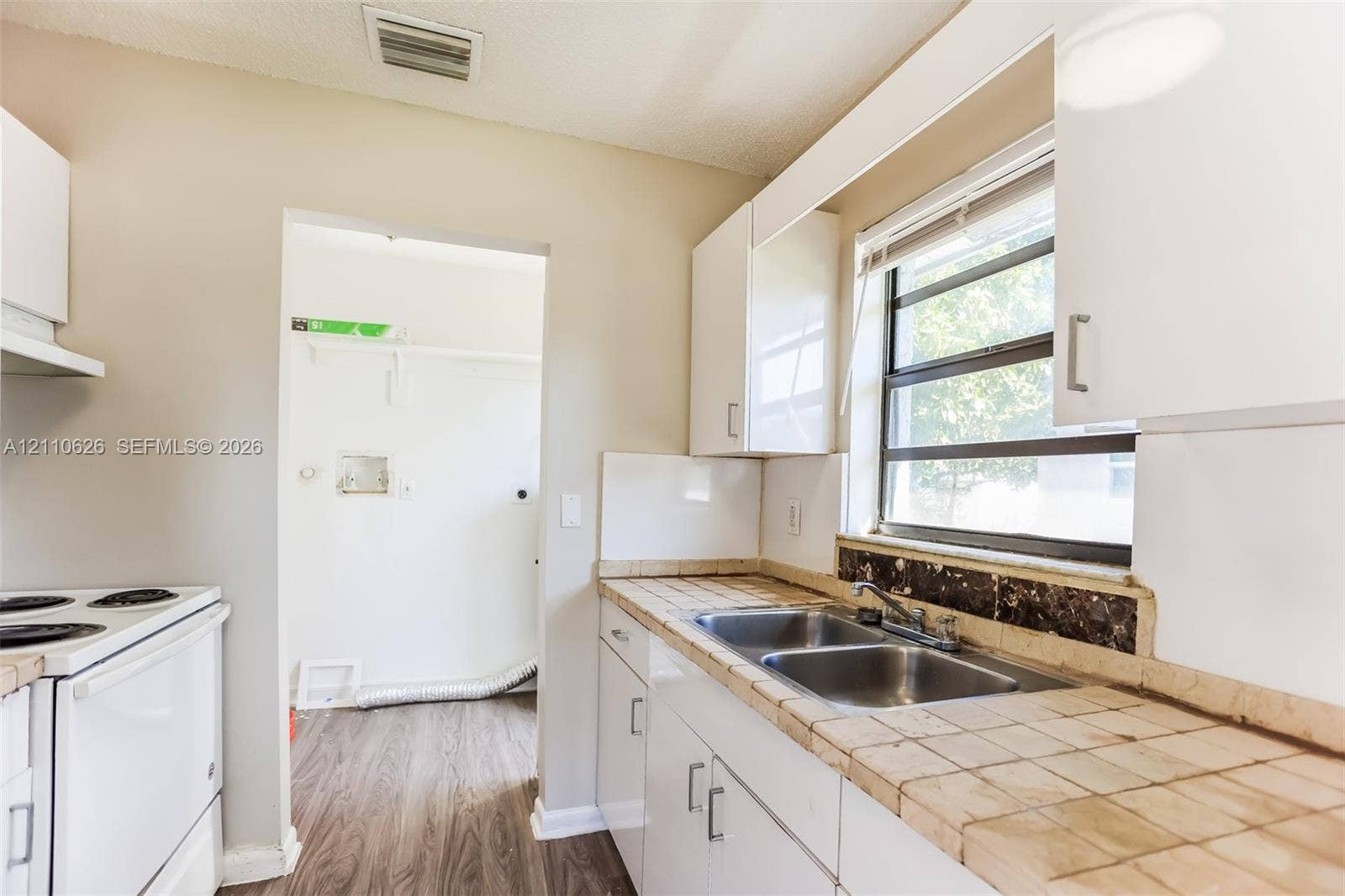 1301 NW 2nd Street, Dania, Dania Beach, FL 33004 Kitchen featuring white cabinetry, tiled countertops, double-basin stainless steel sink, and wood-finish flooring