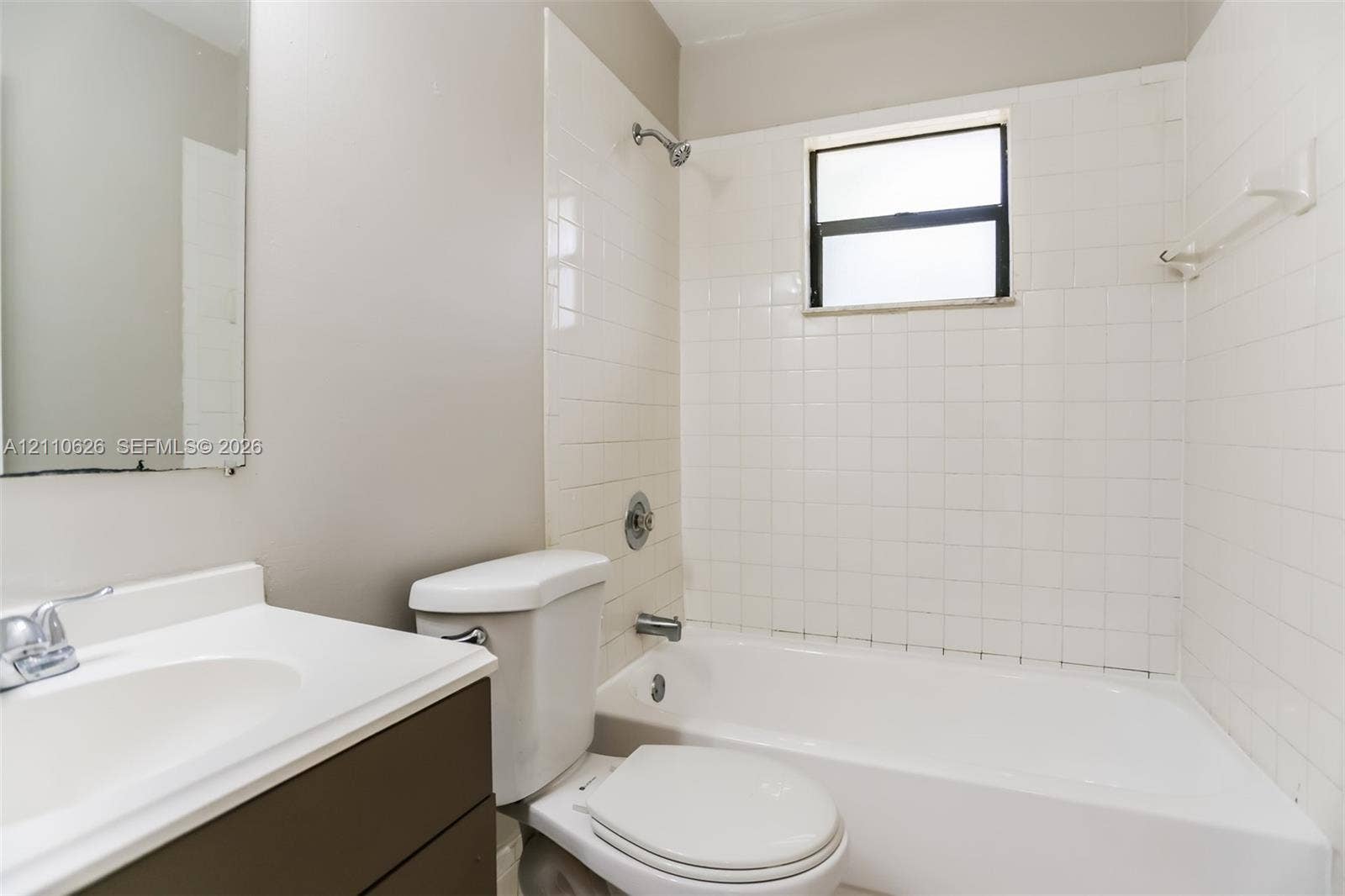 1301 NW 2nd Street, Dania, Dania Beach, FL 33004 Bathroom featuring a white bathtub, white wall tiling, single-basin vanity with a white countertop, and a built-in window