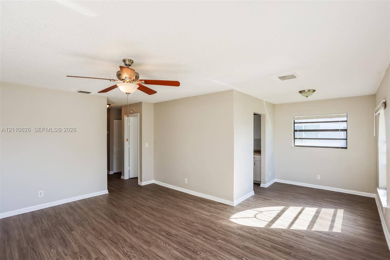 1301 NW 2nd Street, Dania, Dania Beach, FL 33004 Neutral-toned interior space featuring wood-finish flooring, a ceiling fan with integrated lighting, and horizontal slatted windows