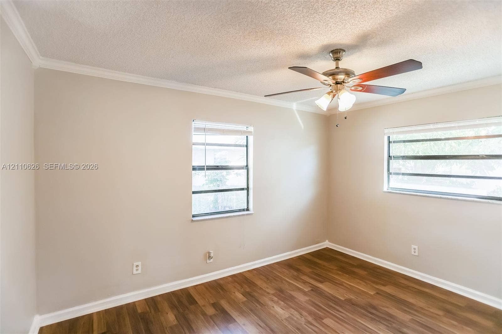 1301 NW 2nd Street, Dania, Dania Beach, FL 33004 Room featuring wood-finish flooring, dual windows with blinds, and a ceiling-mounted fan with integrated lighting