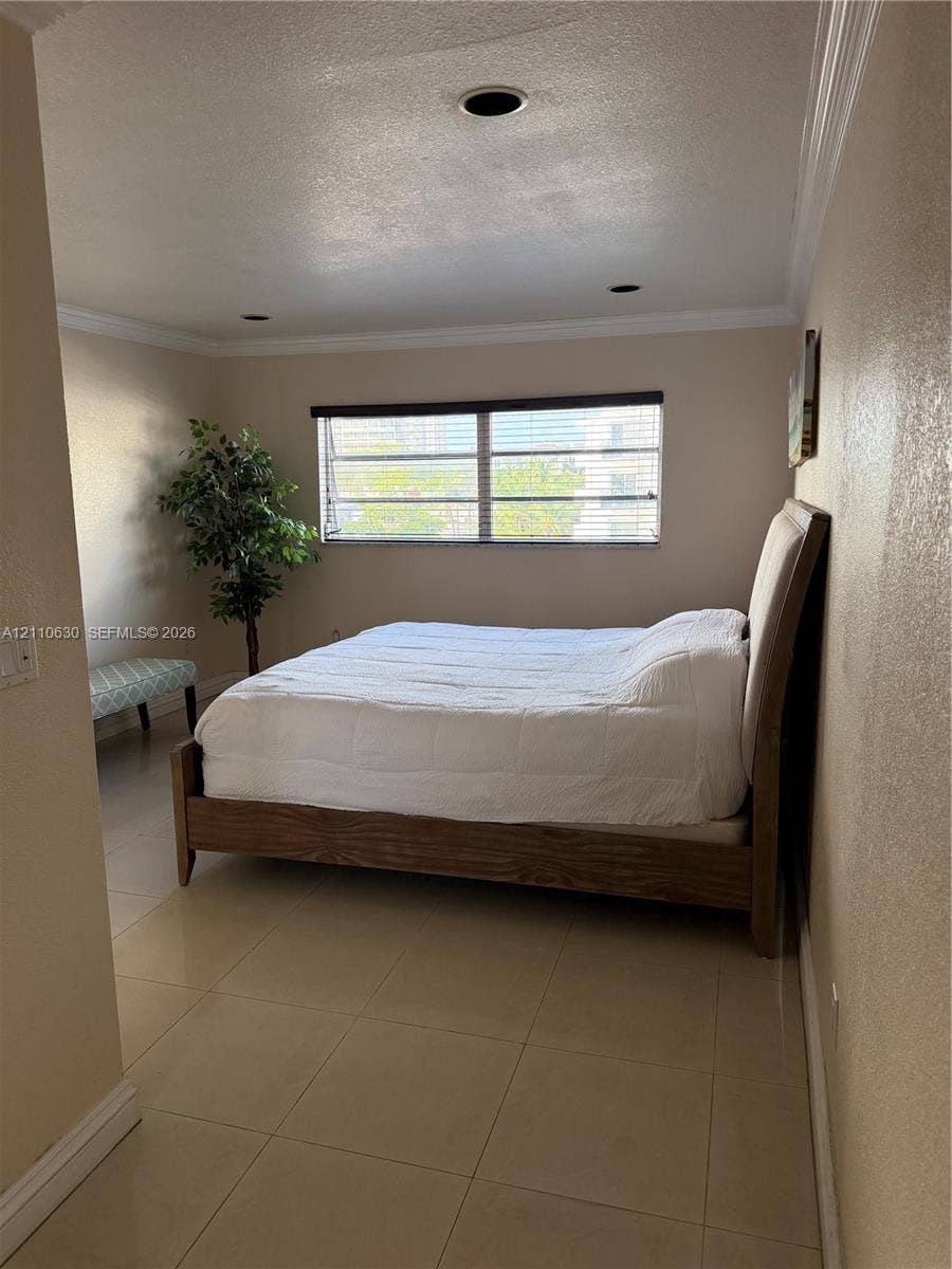 3601 NE 170th Street, #407, North Miami Beach, FL 33160 Room featuring neutral-toned walls, crown molding, tile flooring, and recessed lighting