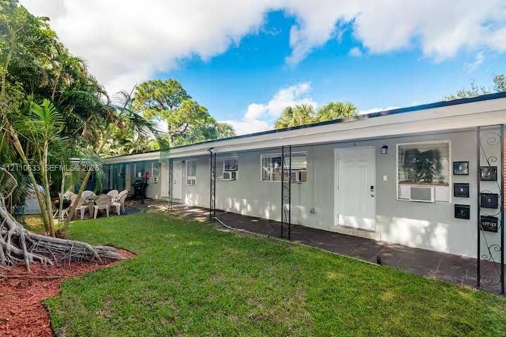 1017 NE 14th Avenue, Fort Lauderdale, FL 33304 Single-story exterior featuring a covered porch, iron support columns, manicured lawn, and mature palm trees