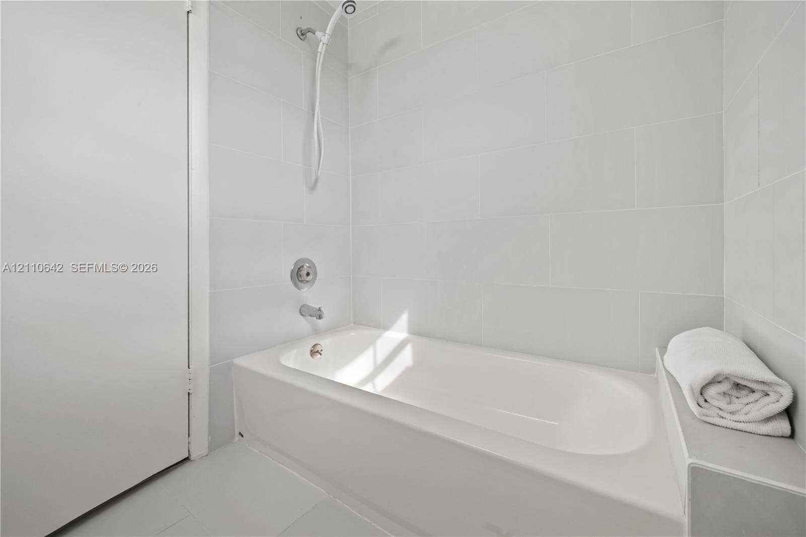 14732 SW 90th Terrace, Miami, FL 33196 Full-size soaking tub featuring a wall-mounted shower head, polished chrome fixtures, and white tile surround