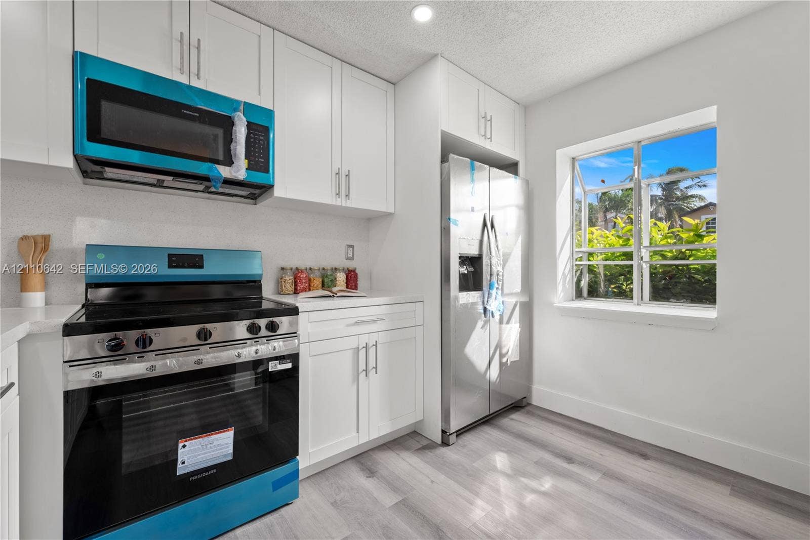 14732 SW 90th Terrace, Miami, FL 33196 Kitchen featuring white shaker-style cabinetry, wood-finish flooring, stainless steel side-by-side refrigerator, slide-in range with glass cooktop, and an over-the-range microwave
