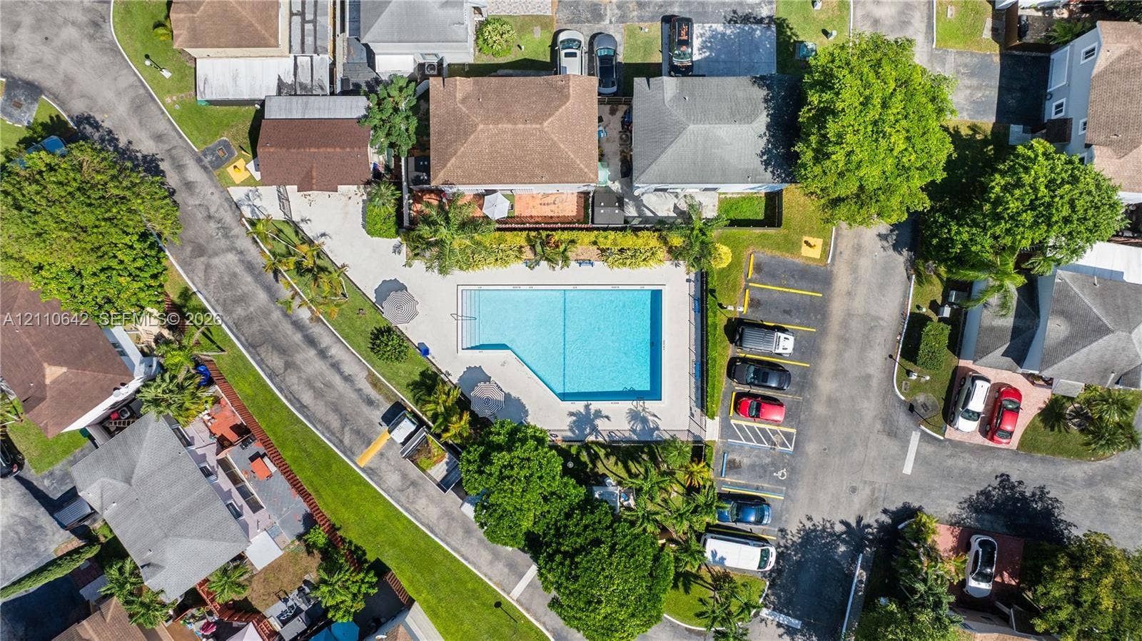 14732 SW 90th Terrace, Miami, FL 33196 Aerial perspective of a community swimming pool featuring a paved pool deck, perimeter fencing, and surrounding mature landscaping