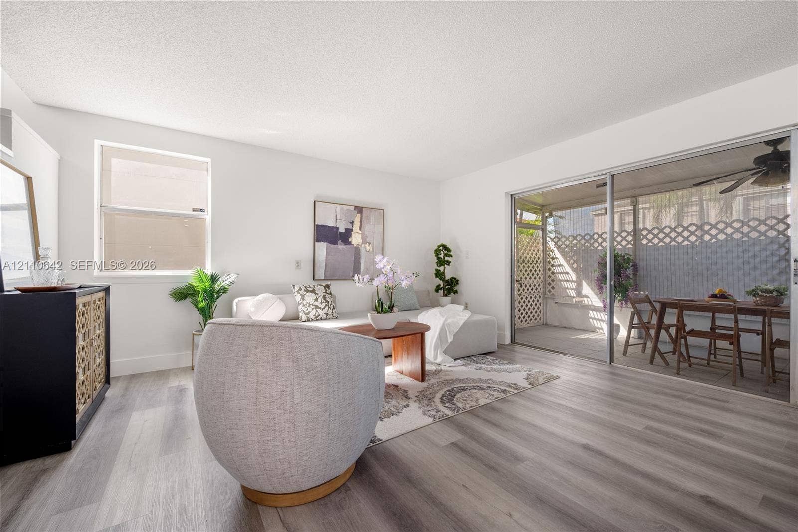14732 SW 90th Terrace, Miami, FL 33196 Living area featuring wood-finish flooring, a single-hung window, and glass sliding doors opening to a covered patio