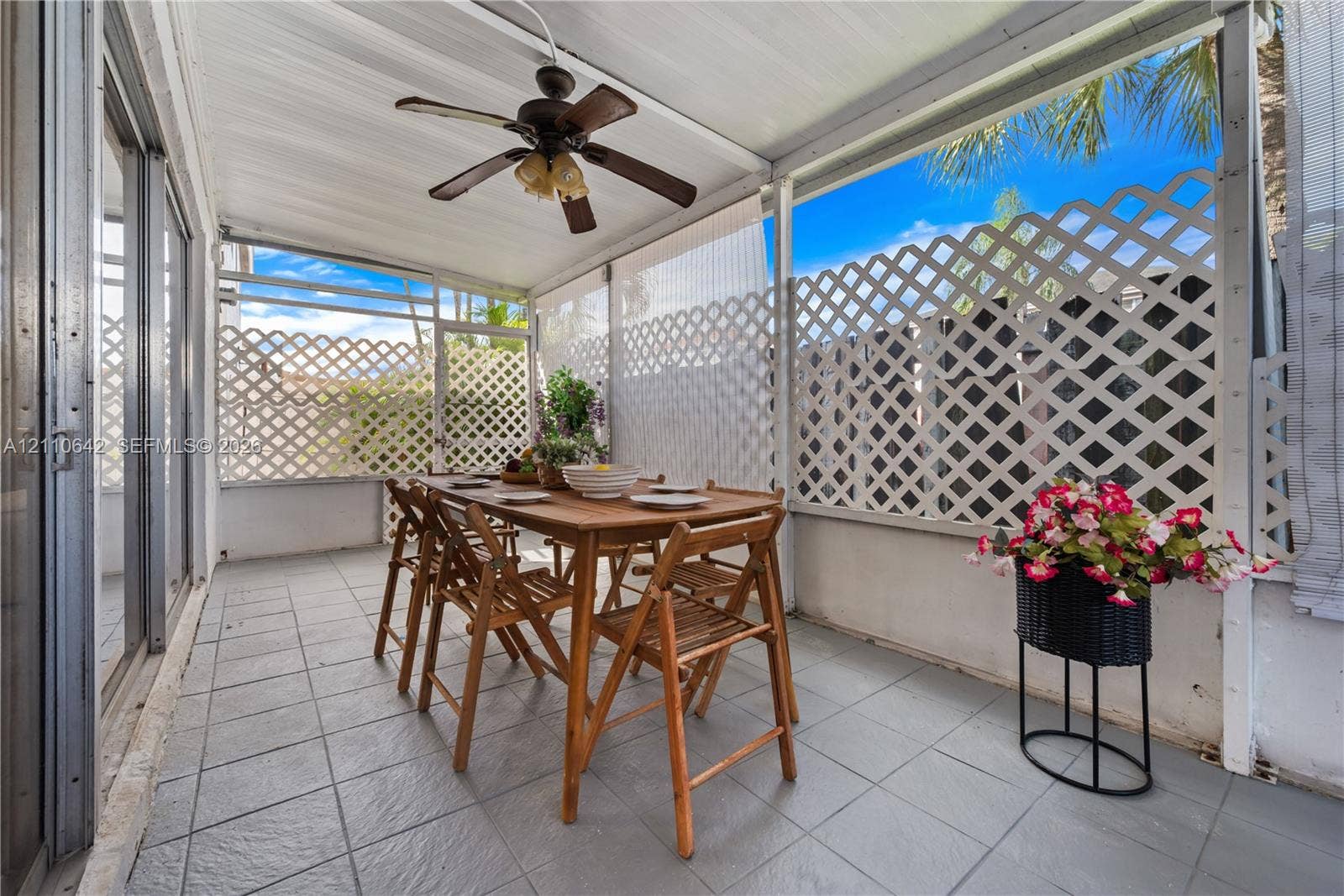 14732 SW 90th Terrace, Miami, FL 33196 Covered patio featuring ceramic tile flooring, built-in ceiling fan with integrated lighting, and white lattice privacy screening