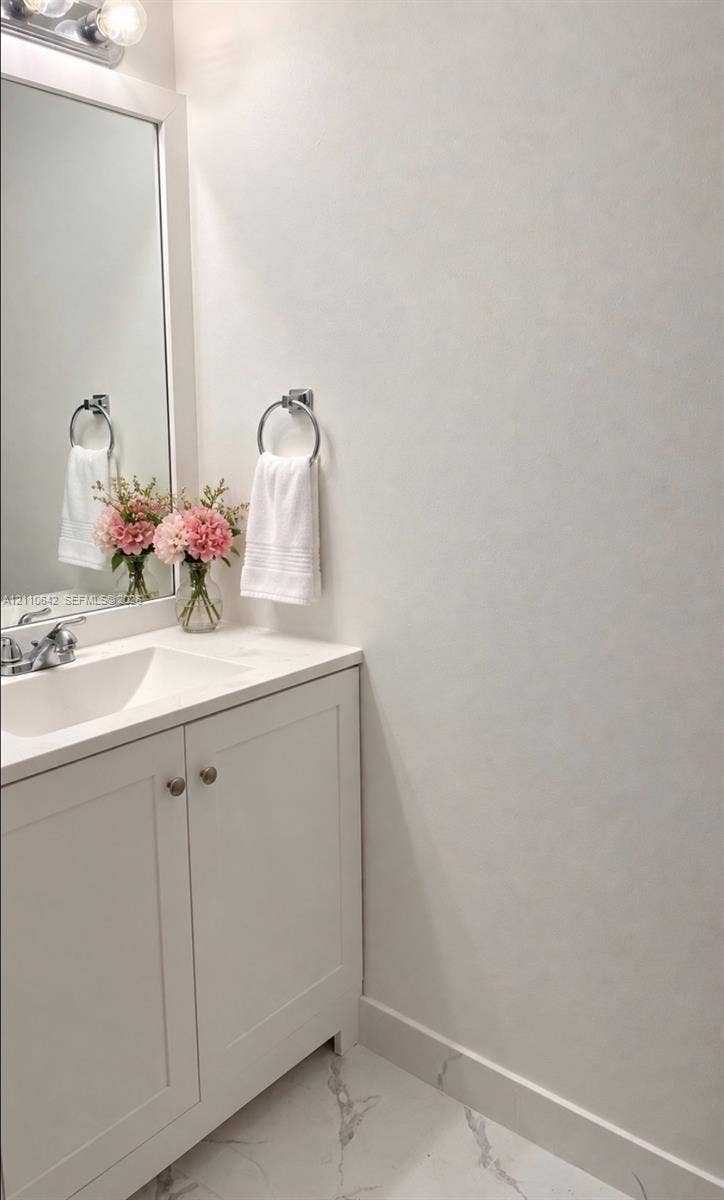 14732 SW 90th Terrace, Miami, FL 33196 White vanity cabinet with a stone-composite countertop, integrated rectangular sink, chrome-finished faucet, framed mirror, and polished stone-finish floor tile
