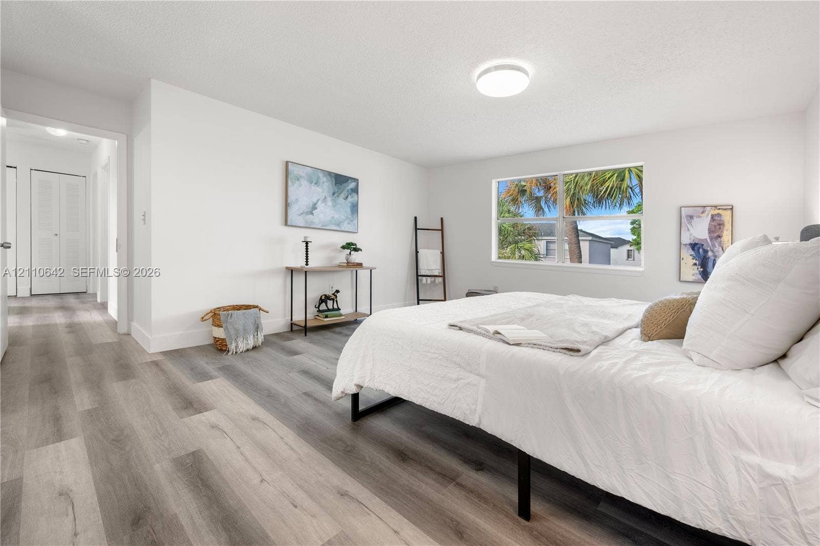 14732 SW 90th Terrace, Miami, FL 33196 Neutral-toned wood-finish flooring, crisp white walls, dual-panel closet doors, and large single-hung window featuring outdoor palm tree greenery