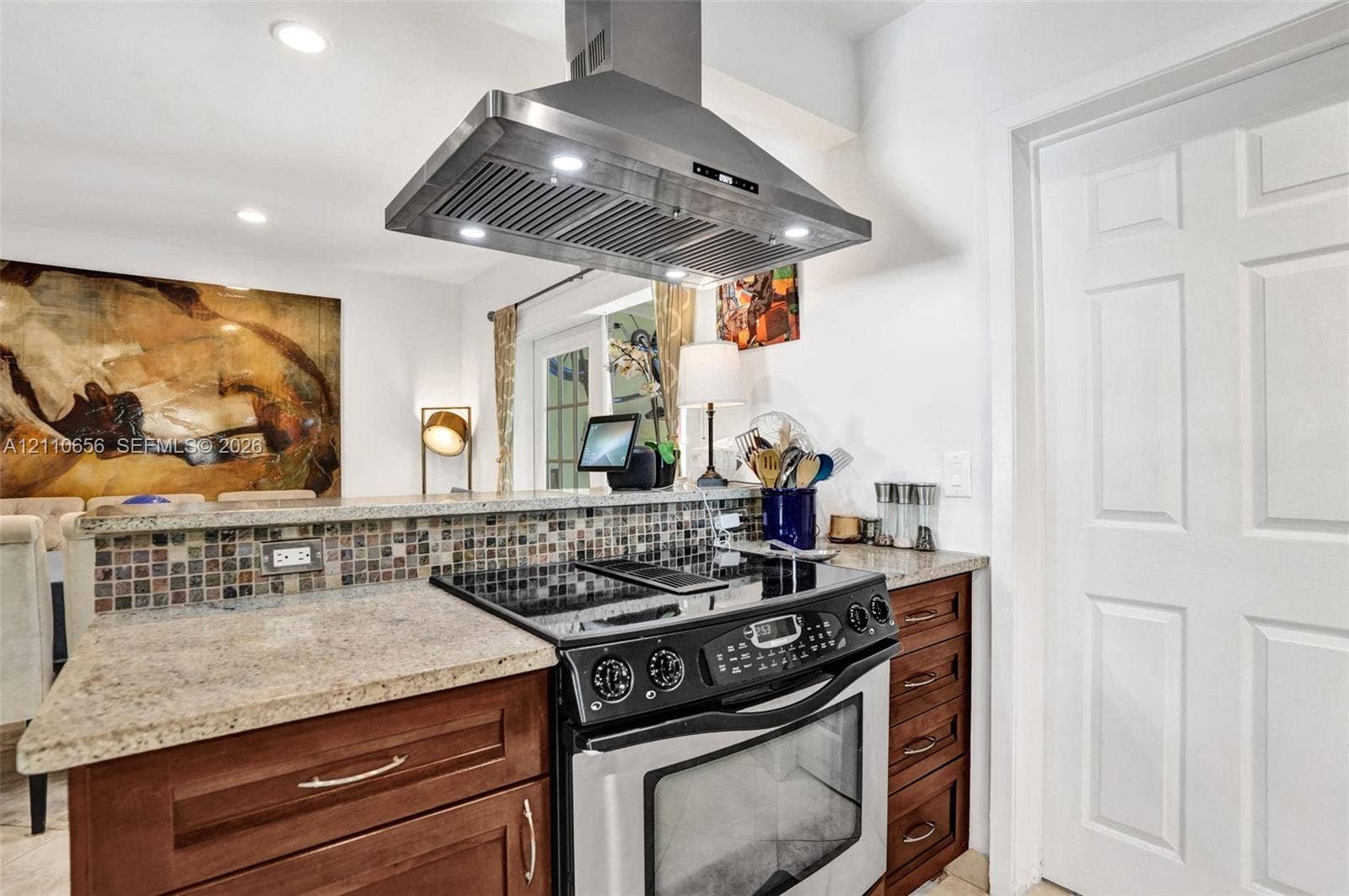 30 NE 48th Court, Oakland Park, FL 33334 Kitchen featuring wood cabinetry, stone countertops, a mosaic tile backsplash, a stainless steel range, and a stainless steel range hood