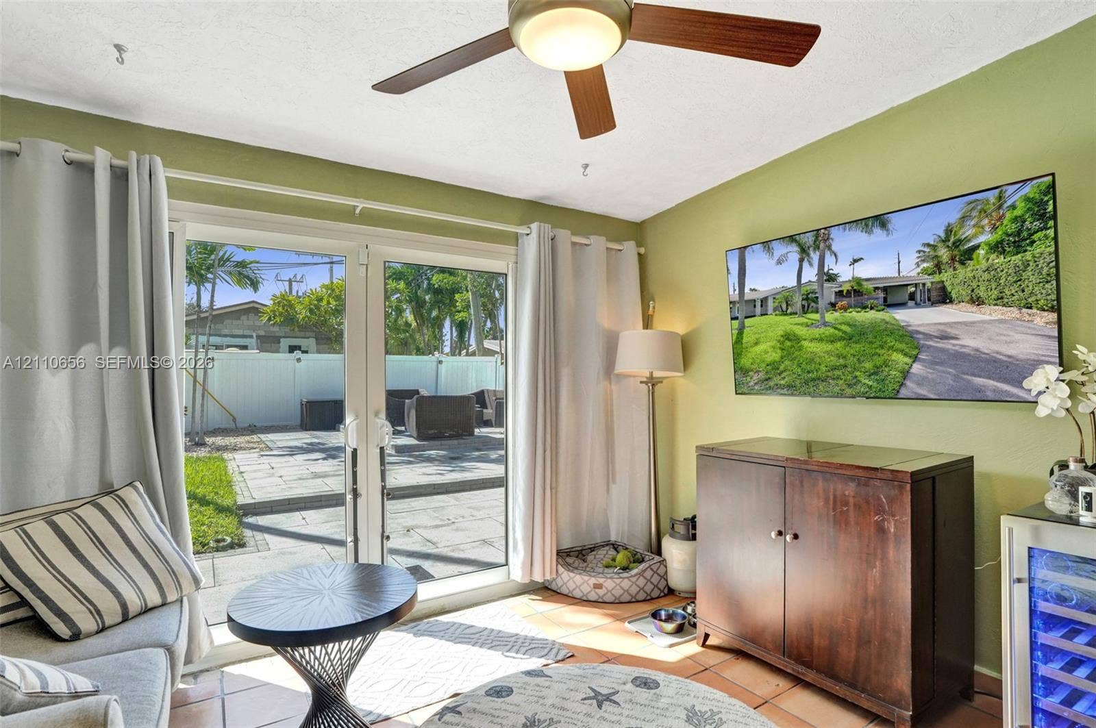 30 NE 48th Court, Oakland Park, FL 33334 Double glass patio doors featuring white frames, ceiling fan with light fixture, and tile flooring