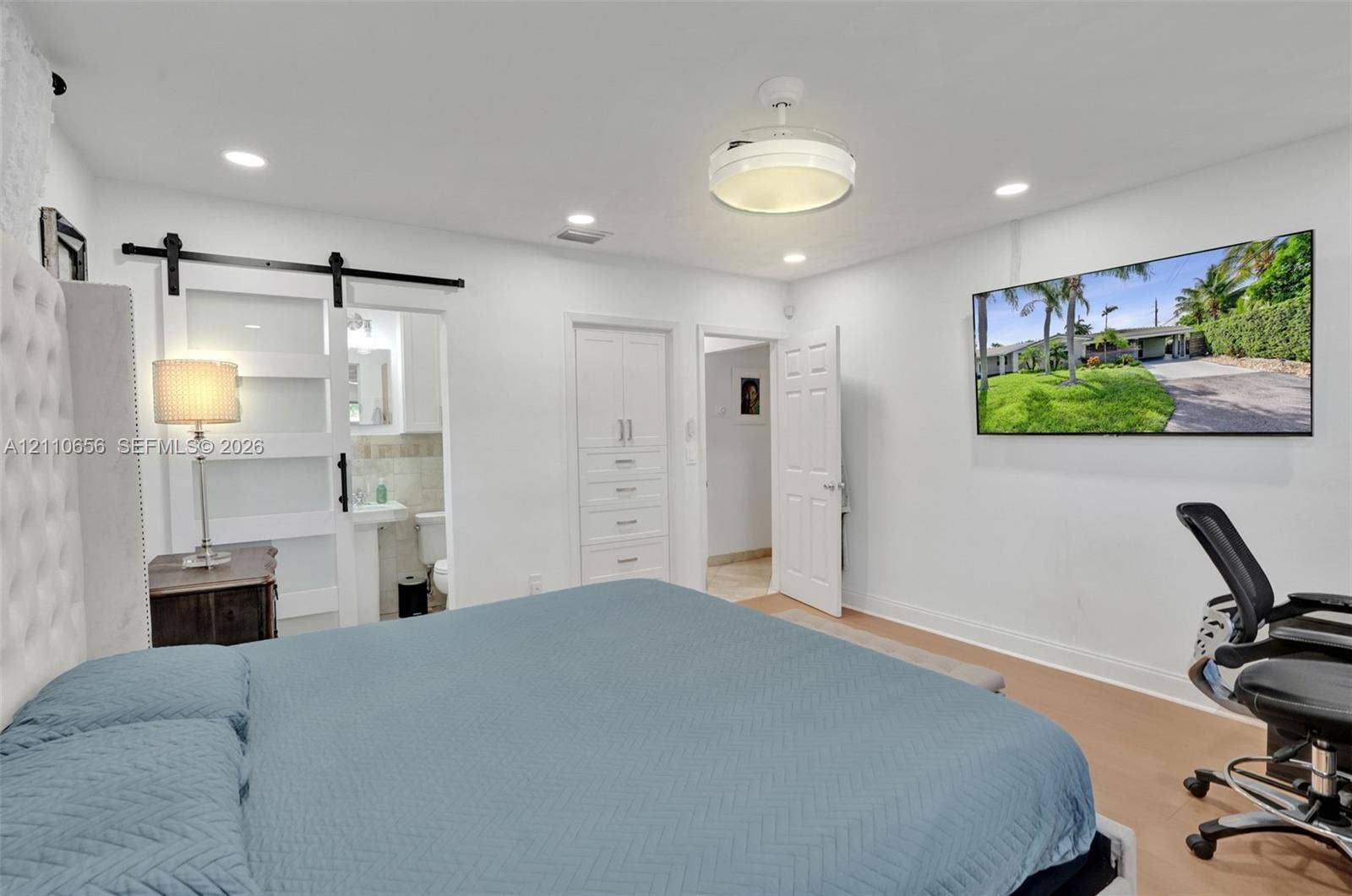 30 NE 48th Court, Oakland Park, FL 33334 Interior featuring recessed lighting, a ceiling-mounted drum light fixture, sliding frosted-glass barn door with matte black hardware, and built-in floor-to-ceiling cabinetry