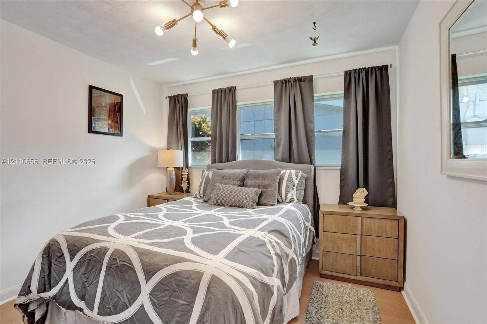 30 NE 48th Court, Oakland Park, FL 33334 Multi-pane windows, wood-finish flooring, and a modern six-light sputnik-style chandelier