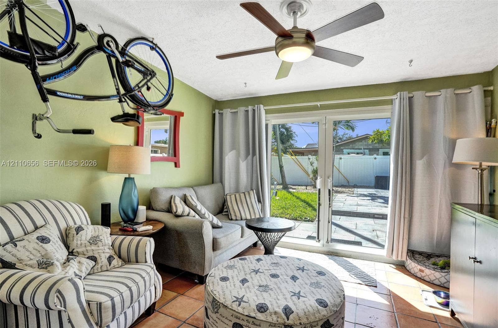 30 NE 48th Court, Oakland Park, FL 33334 Sliding glass patio doors, neutral tile flooring, and a modern ceiling fan with integrated lighting