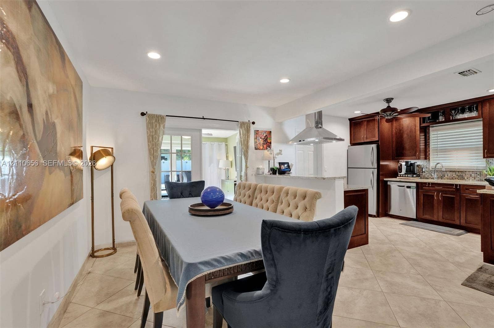 30 NE 48th Court, Oakland Park, FL 33334 Kitchen featuring dark wood cabinetry, stainless steel appliances, a stainless steel range hood, stone-finish countertops, and tile flooring