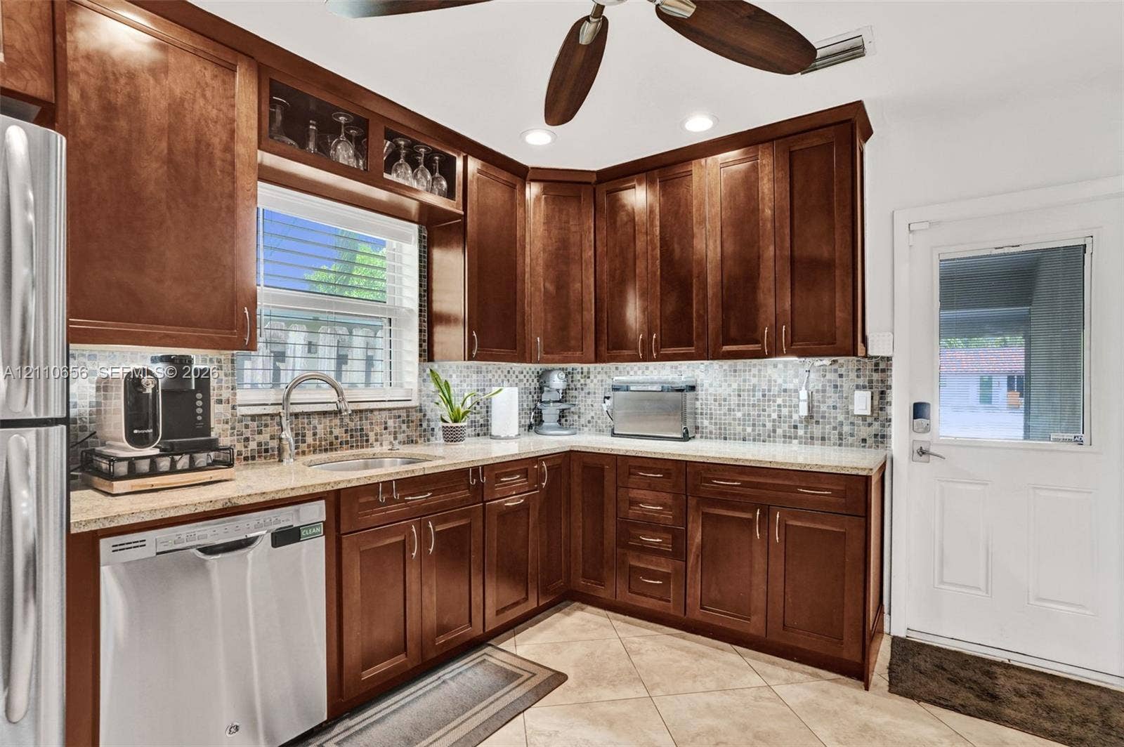 30 NE 48th Court, Oakland Park, FL 33334 Kitchen featuring raised-panel wood cabinetry, mosaic tile backsplash, solid-surface countertops, recessed lighting, and tile flooring