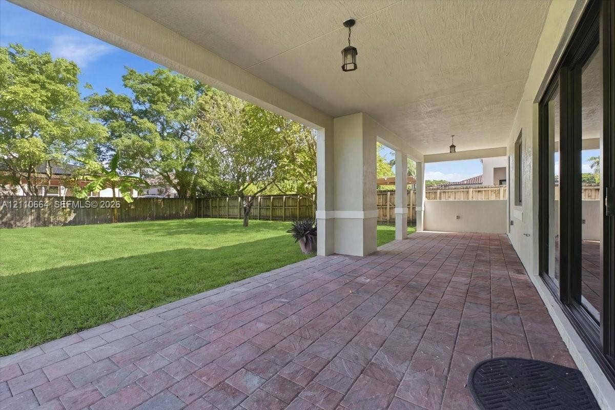 Spacious covered patio with paver flooring, opening to a fully fenced backyard with ample room for a custom pool and an expansive outdoor entertaining retreat
