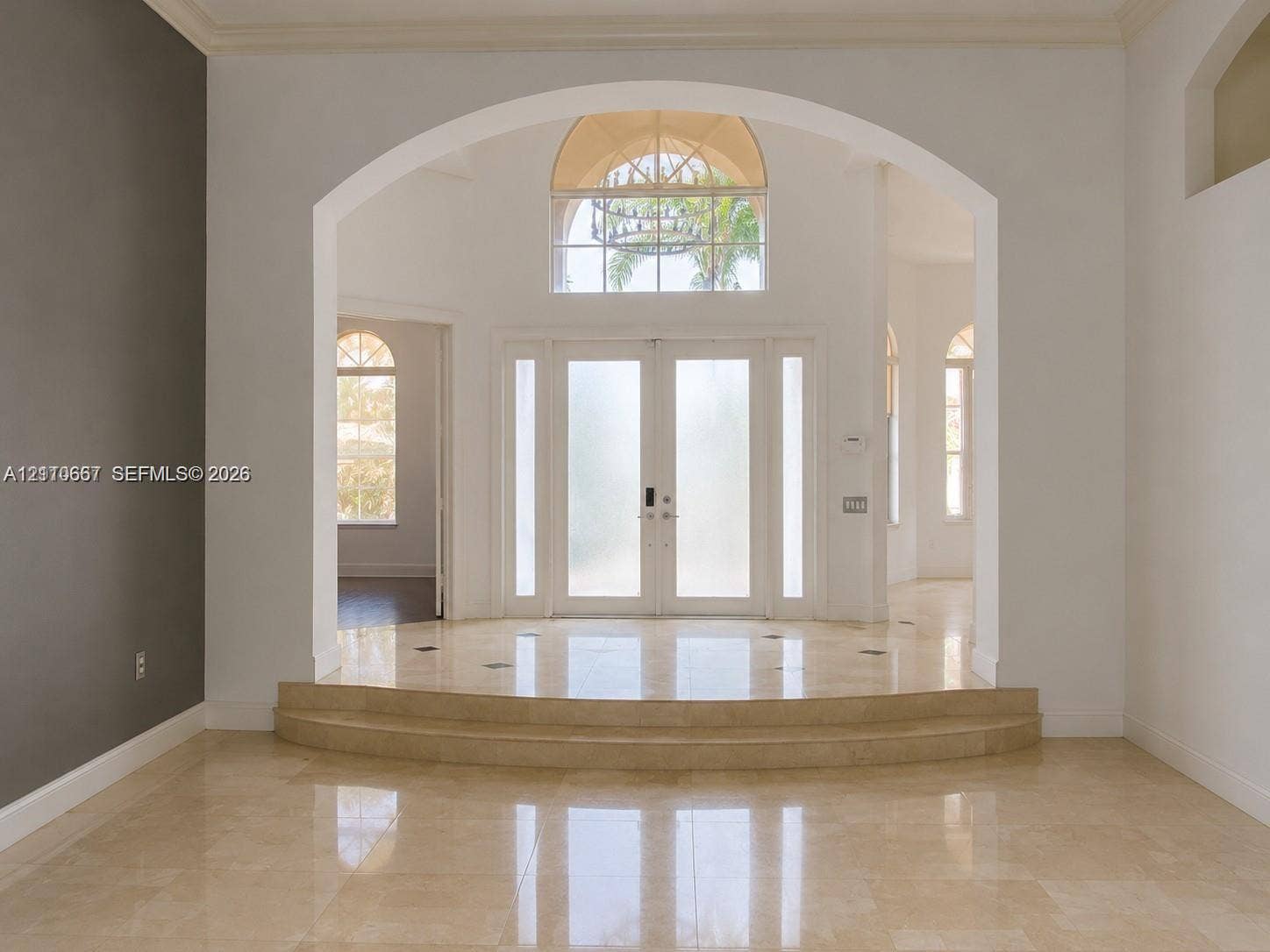 Living area featuring polished tile flooring, a recessed tray ceiling with integrated lighting, and a floor-to-ceiling picture window overlooking a swimming pool and greenery
