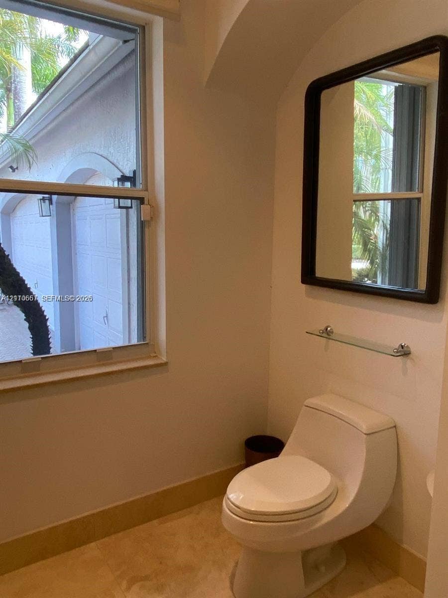Tray ceiling with recessed lighting, wood-finish flooring, arched entryway, and large windows with exterior pool access