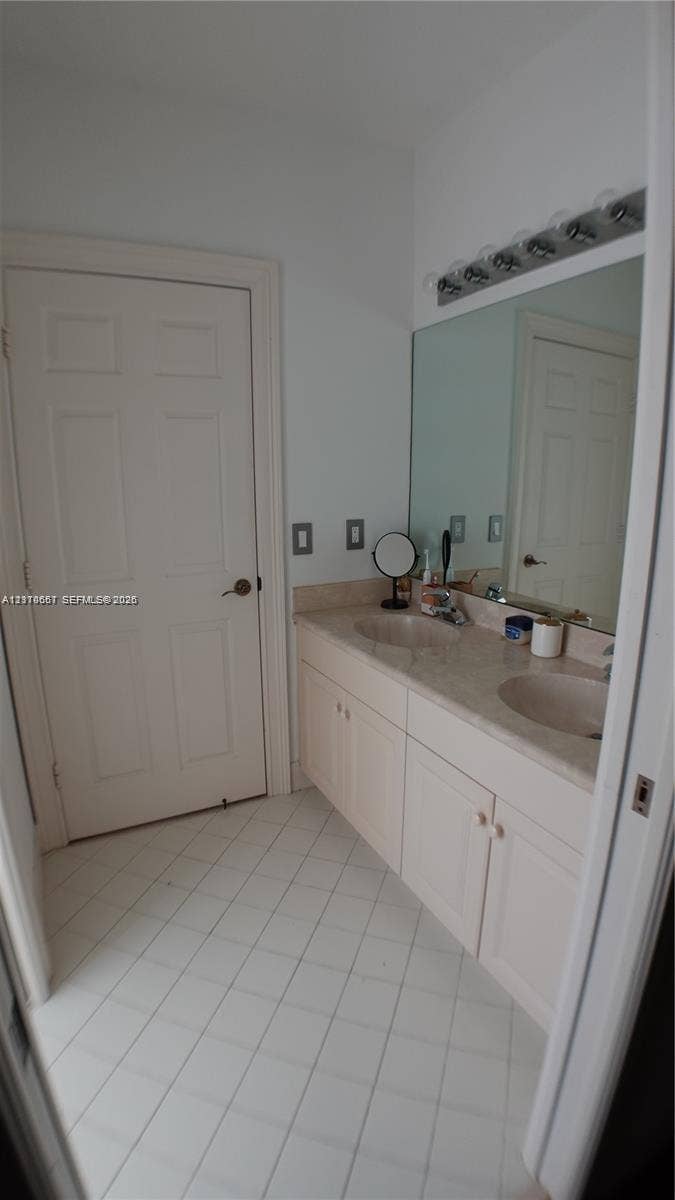 Laundry area featuring flat-panel wood-finish cabinetry, a white countertop, an undermount stainless steel sink, and a high-arc matte black faucet