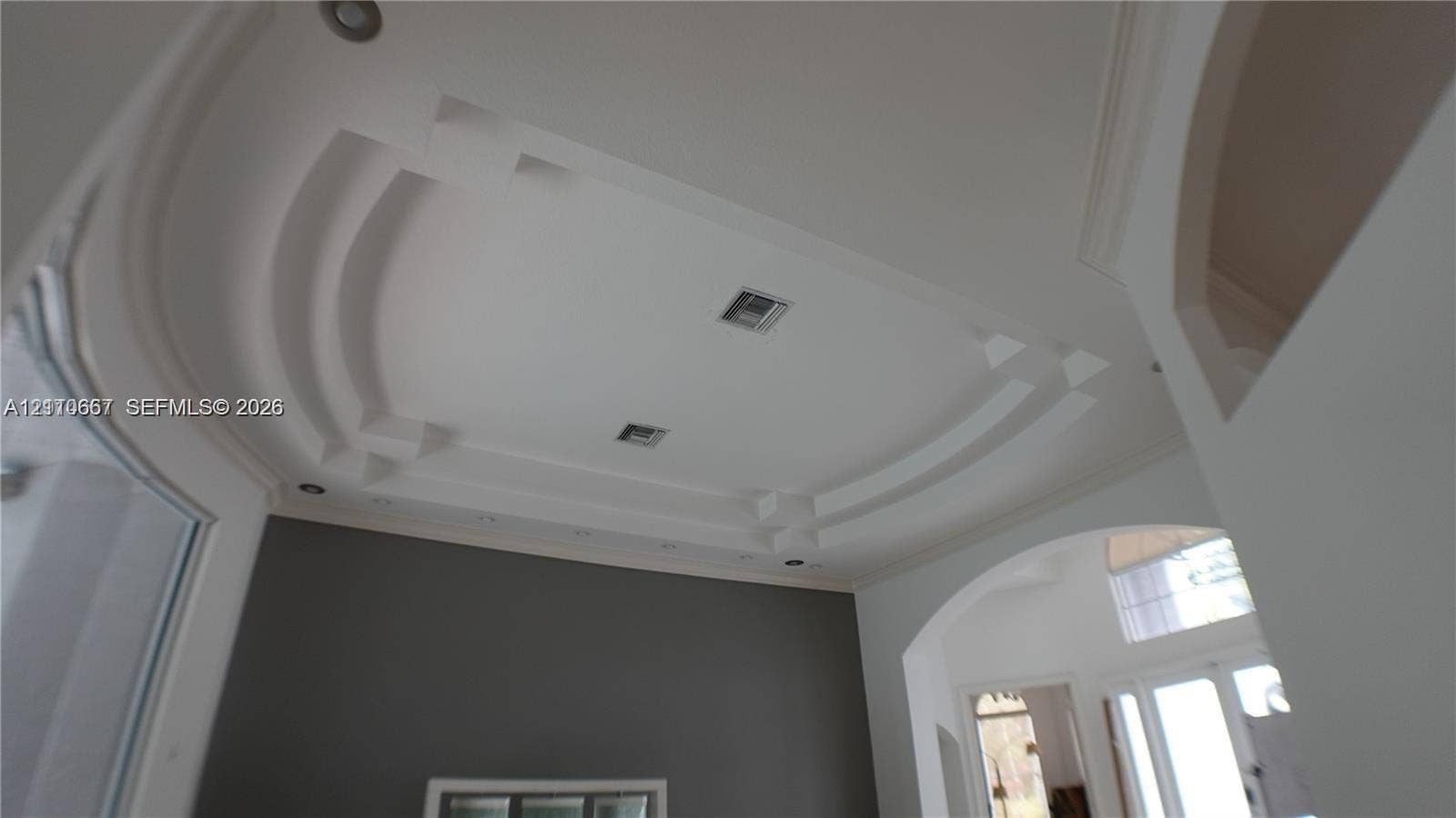 Open-concept interior featuring a textured stone accent wall, polished tile flooring, recessed lighting, four modern pendant lights, and a high ceiling with an integrated ceiling fan