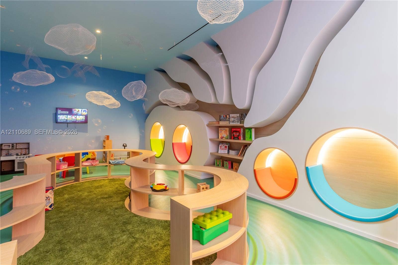 Custom sculptural wall molding with integrated circular niches, tiered curved wood-finish shelving, recessed accent lighting, and cloud-patterned ceiling fixtures
