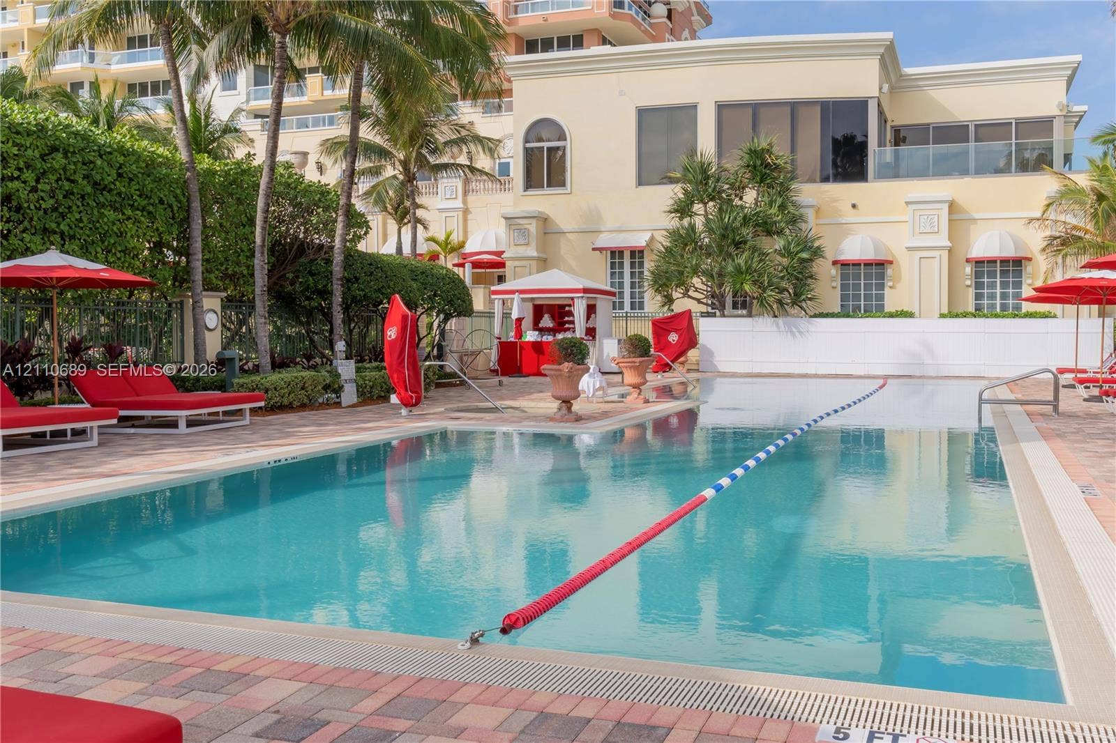 Swimming pool with lane marker, multi-tone paver deck, and mature palm tree landscaping
