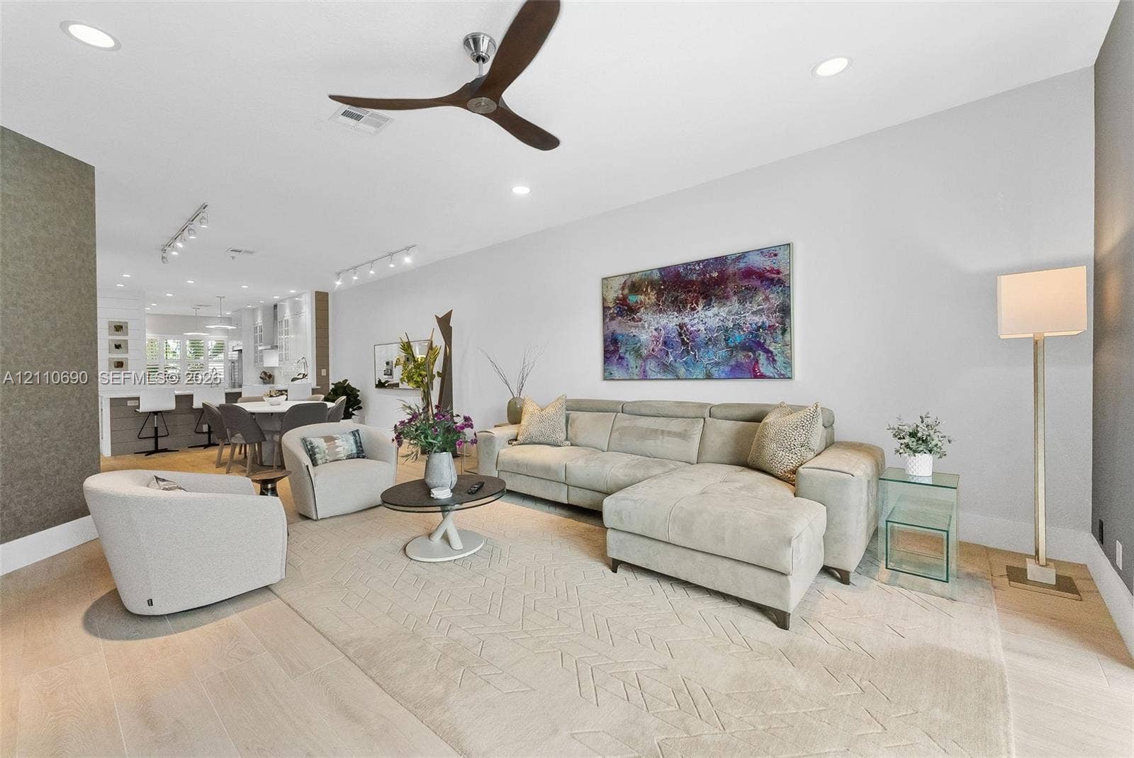 Open-concept interior featuring light-toned wood-finish flooring, recessed lighting, track lighting, and a contemporary three-blade ceiling fan