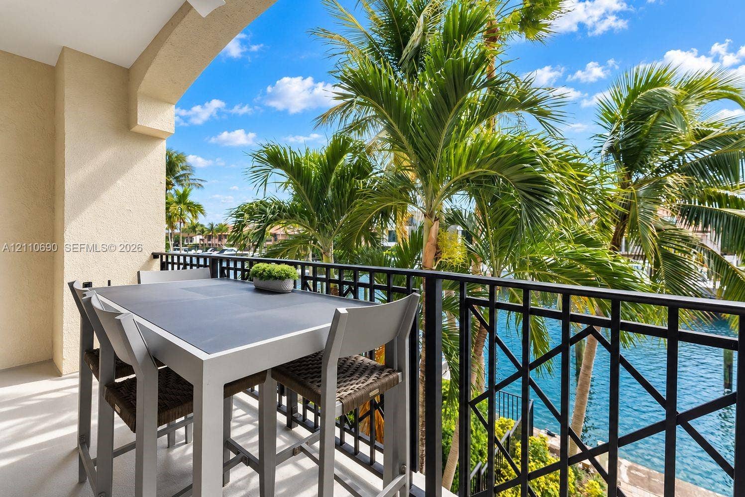 Covered balcony featuring a decorative metal railing, concrete flooring, and water frontage