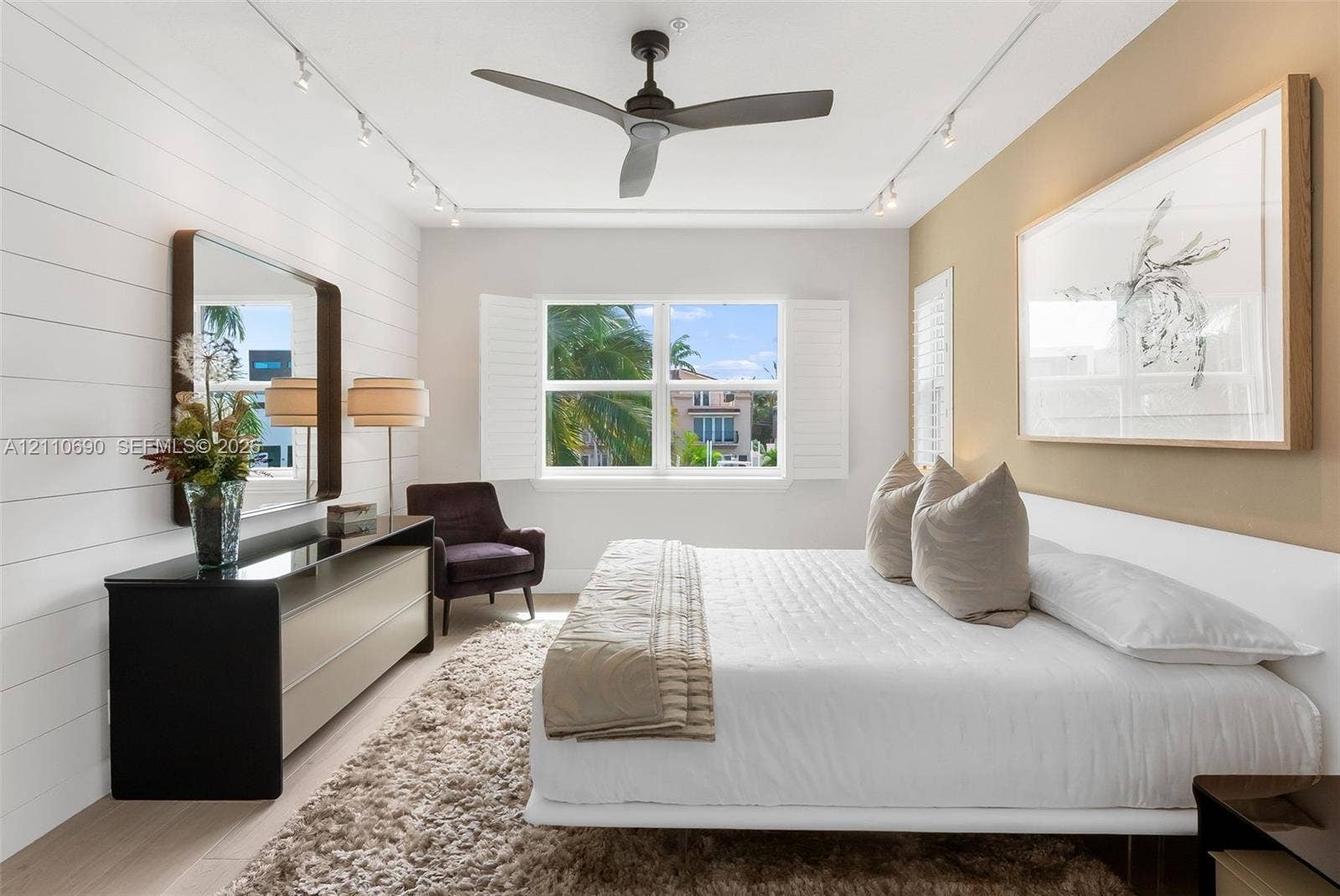 Room featuring horizontal shiplap wall paneling, ceiling-mounted track lighting, a matte finish ceiling fan, and window-mounted interior shutters