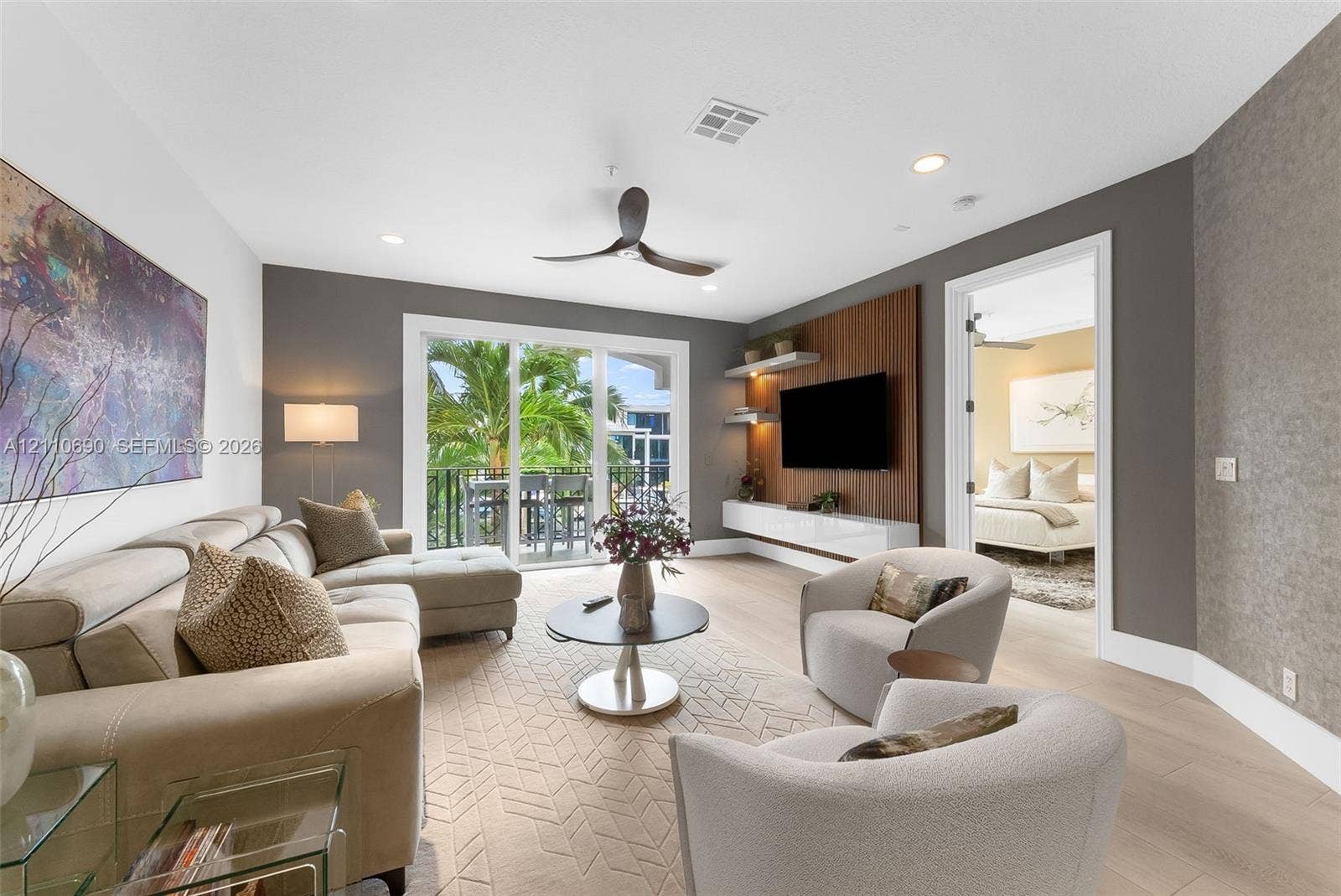 Living area featuring wood-finish flooring, a built-in media wall with wood paneling, floating cabinetry, recessed lighting, and sliding glass doors