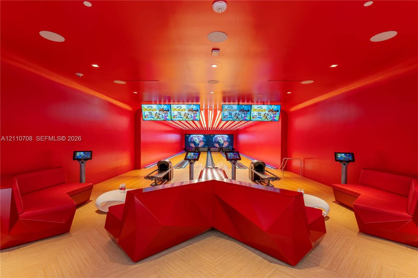 Private bowling alley featuring two lanes, built-in display screens, integrated ceiling lighting, and chevron-patterned wood-finish flooring