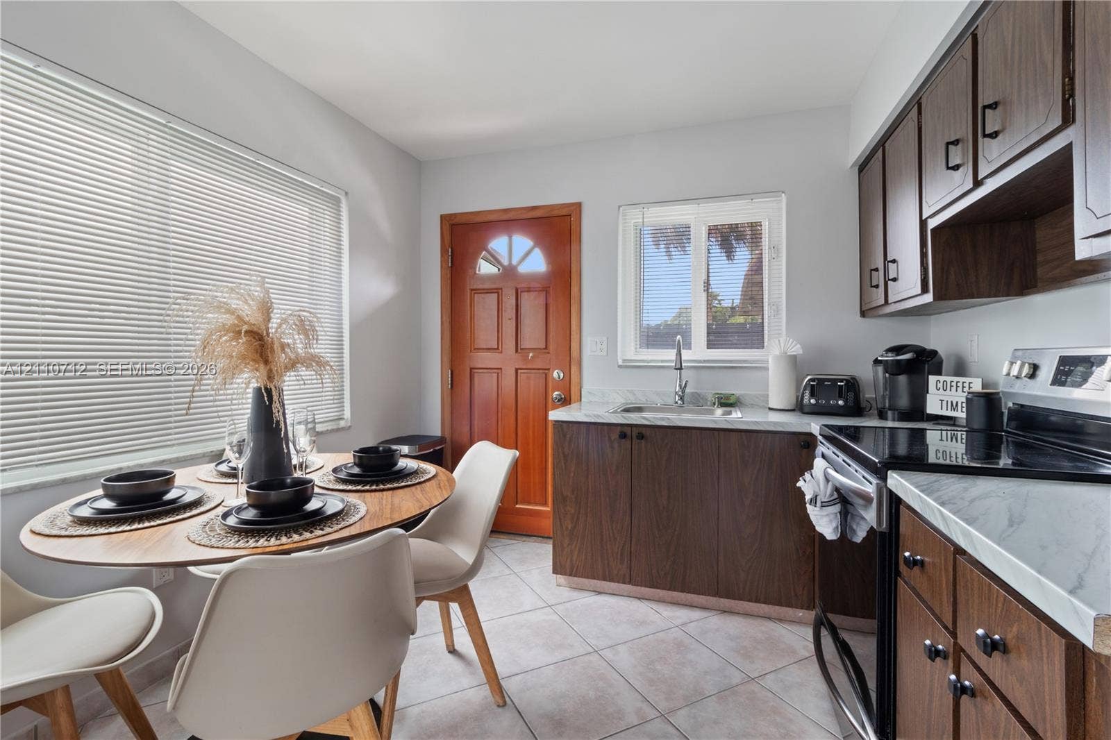 Kitchen featuring wood cabinetry, stone-finish countertops, tile flooring, and a glass-paneled wooden door