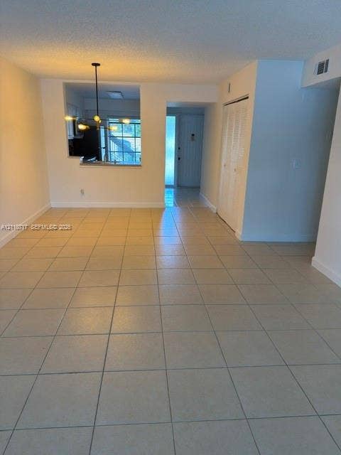 2297 SW 15th Street, #125, Deerfield Beach, Deerfield Beach, FL 33442 Open-concept area featuring neutral ceramic tile flooring, a multi-arm pendant light fixture, and a pass-through opening