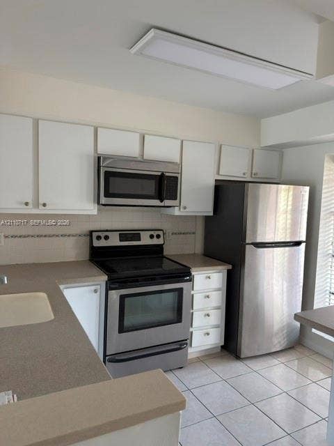 2297 SW 15th Street, #125, Deerfield Beach, Deerfield Beach, FL 33442 Kitchen featuring white cabinetry, solid-surface countertops, stainless steel appliances, ceramic tile flooring, and a recessed ceiling light fixture