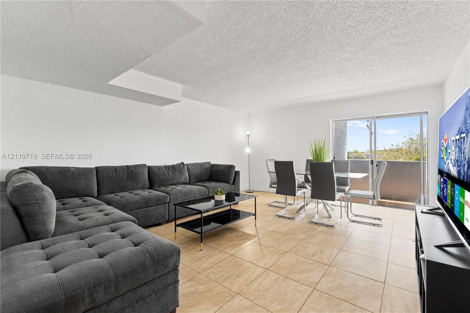 9375 Fontainebleau Boulevard, #L314, Miami, FL 33172 Living area featuring neutral tile flooring and sliding glass doors with access to an exterior balcony