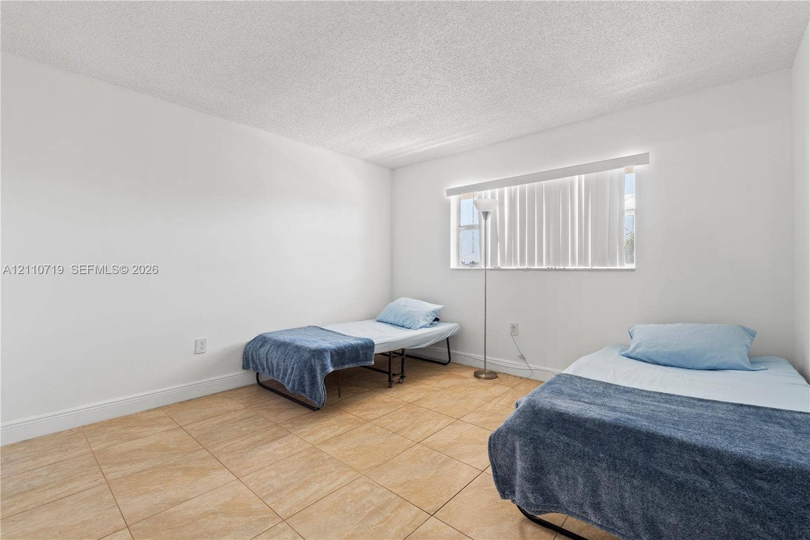 9375 Fontainebleau Boulevard, #L314, Miami, FL 33172 Neutral-toned tile flooring, textured ceiling, and single-pane window with horizontal blinds