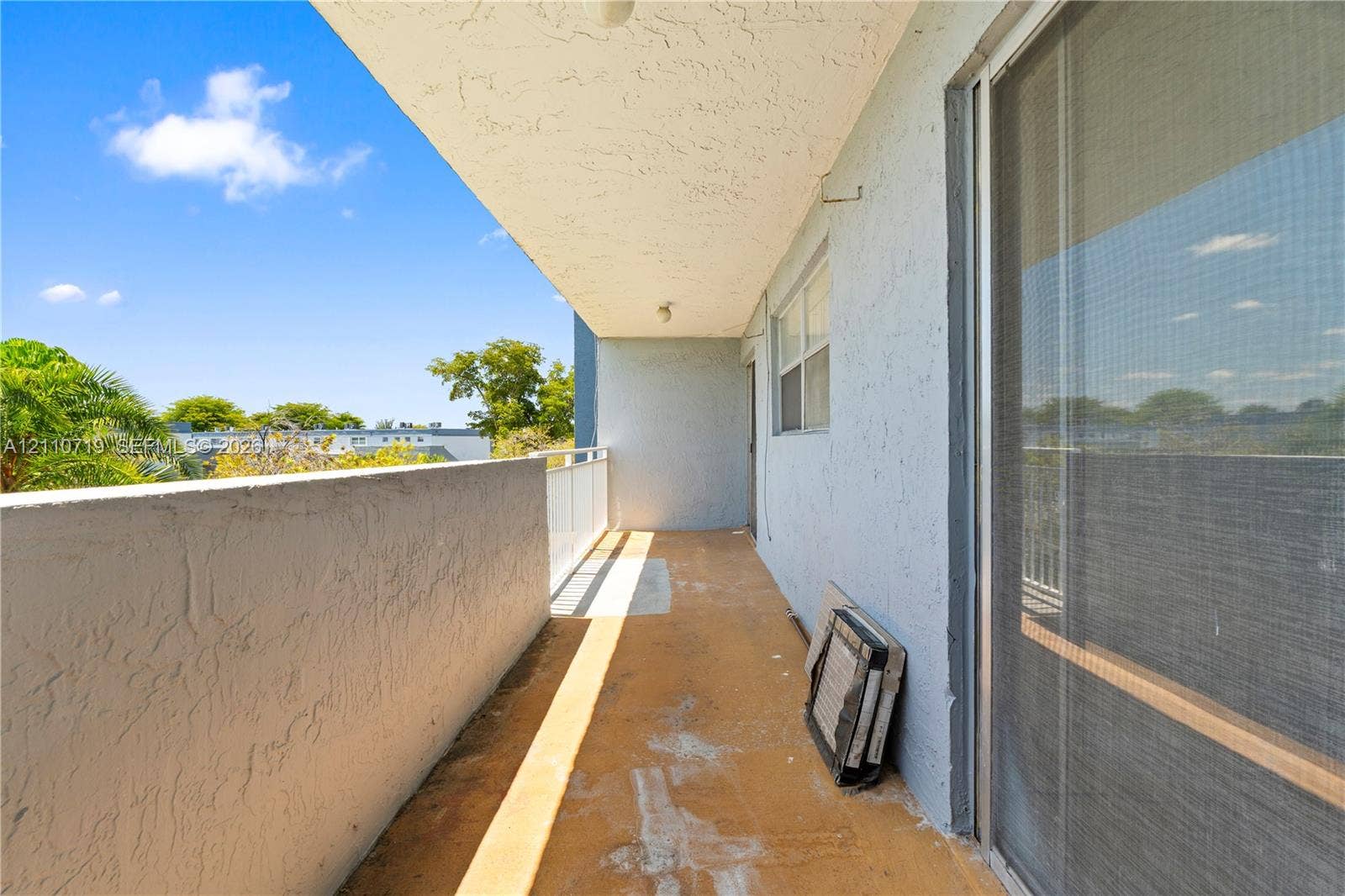 9375 Fontainebleau Boulevard, #L314, Miami, FL 33172 Covered balcony featuring concrete flooring, a solid masonry wall, and a sliding glass door