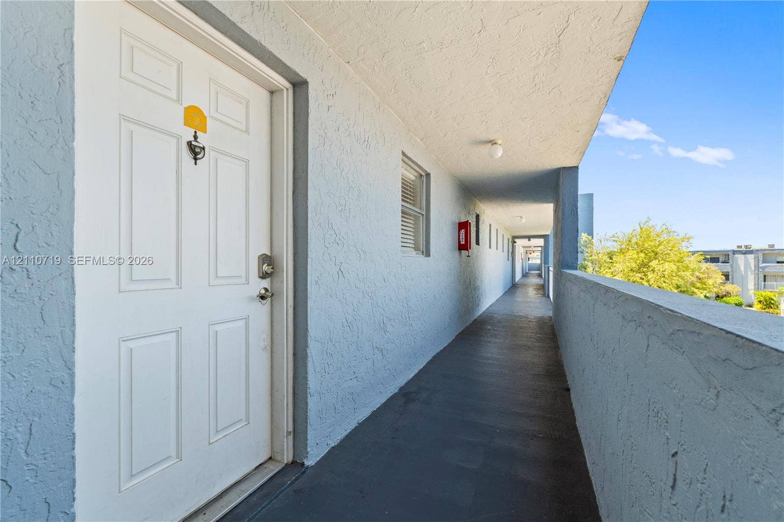 9375 Fontainebleau Boulevard, #L314, Miami, FL 33172 Exterior covered walkway featuring a textured stucco finish, integrated ceiling lighting, and a paneled entry door with hardware
