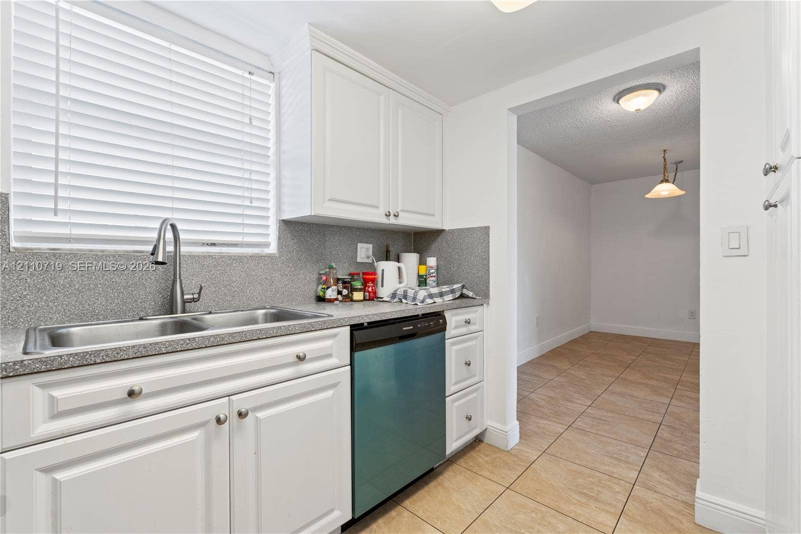 9375 Fontainebleau Boulevard, #L314, Miami, FL 33172 Kitchen featuring white shaker-style cabinetry, a stone-finish countertop, dual-basin stainless steel sink with a high-arch faucet, integrated dishwasher, and tile flooring
