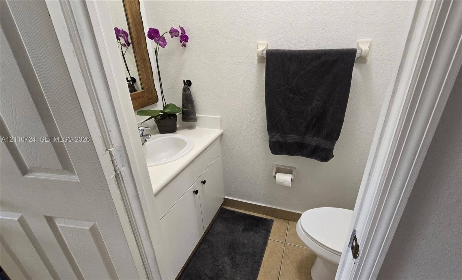 10846 SW 240th Lane, Homestead, FL 33032 Powder room featuring a white vanity cabinet with a solid surface countertop, integrated sink, tile flooring, and wall-mounted hardware