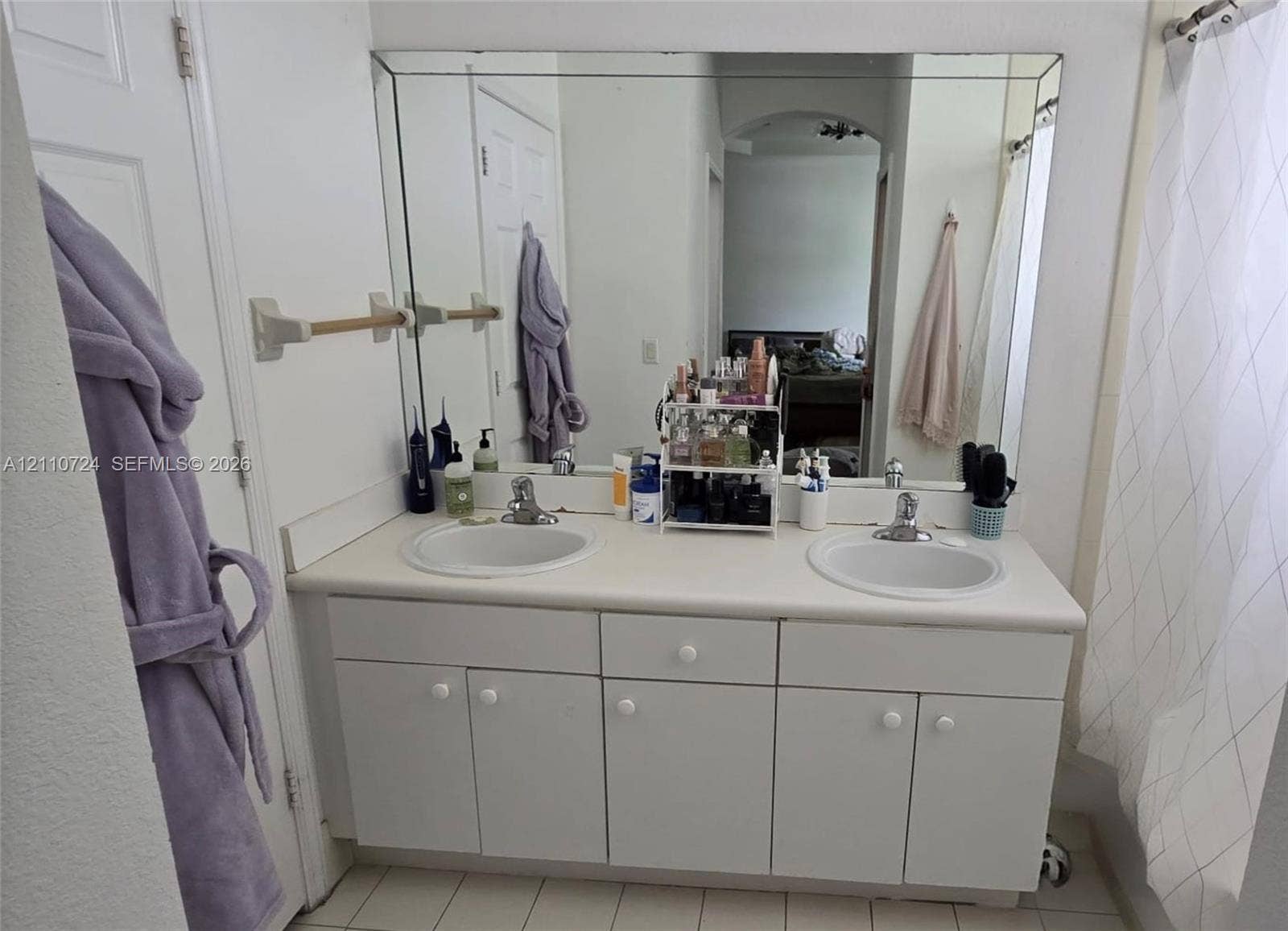 10846 SW 240th Lane, Homestead, FL 33032 Dual-basin vanity featuring a solid surface countertop, white cabinetry with integrated hardware, and a large wall-mounted mirror