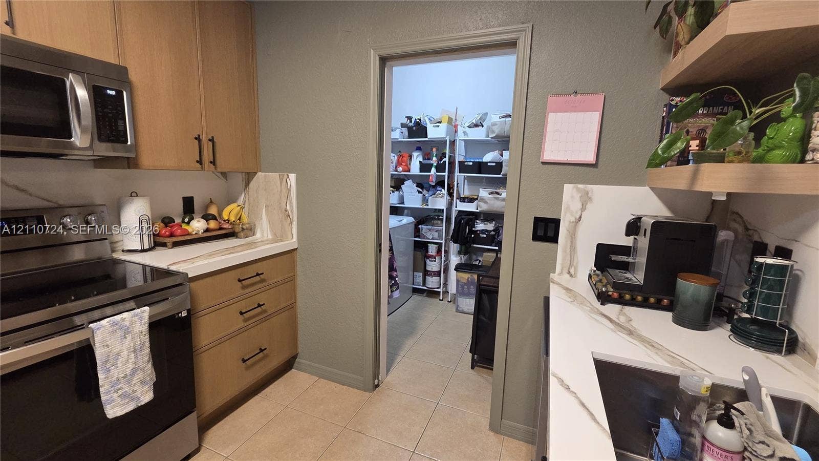 10846 SW 240th Lane, Homestead, FL 33032 Kitchen featuring wood cabinetry, stone-look backsplash, built-in stainless steel appliances, floating shelves, and tile flooring