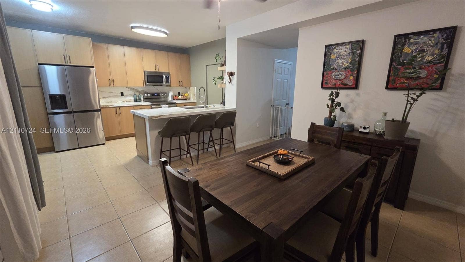 10846 SW 240th Lane, Homestead, FL 33032 Kitchen featuring light-finish cabinetry, stainless steel appliances, a central island with a breakfast bar, and tile flooring